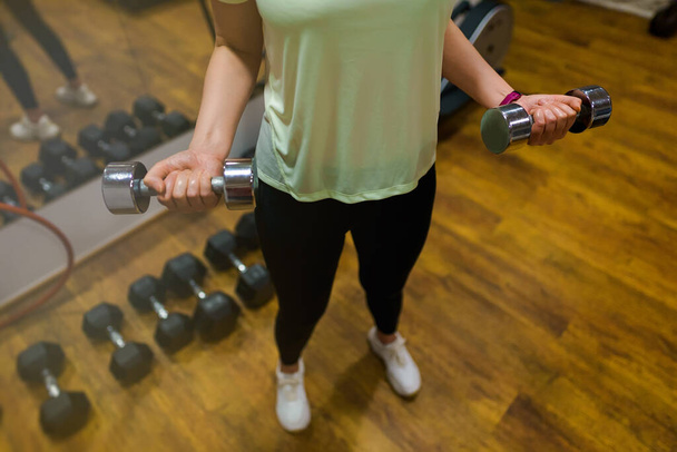 Woman doing exercises with dumbbells for biceps. - Fotó, kép