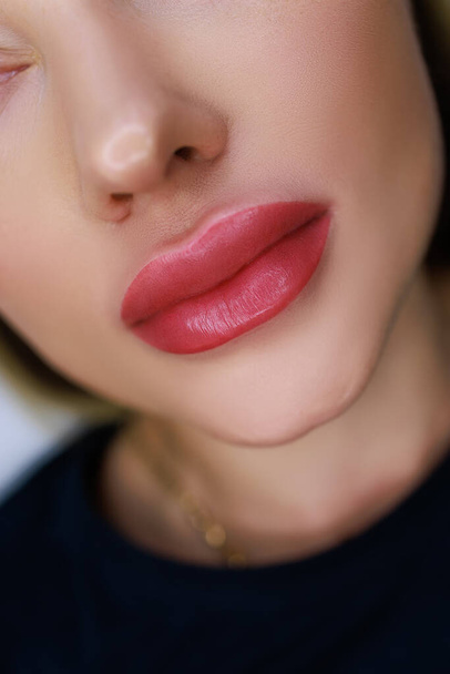 close-up of the lips of a beautiful girl model with the work done on the permanent make-up of the lips - Photo, image