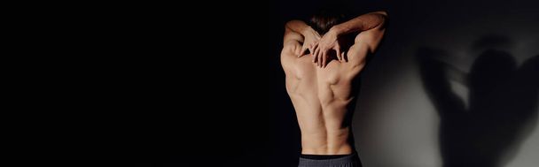 back view of man with muscular body standing on black and grey background, banner - Фото, изображение