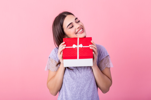 Portrait of young lovely nice sweet glamorous girl lady, wearing gray top, carrying gift box, wondering about surprise. Isolated over bright vivid pink background - Photo, image
