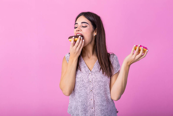Beauty model girl eating colorful donuts. Funny joyful styled woman choosing sweets on pink background. Diet, dieting concept. Junk food, Slimming, weight loss - Fotoğraf, Görsel