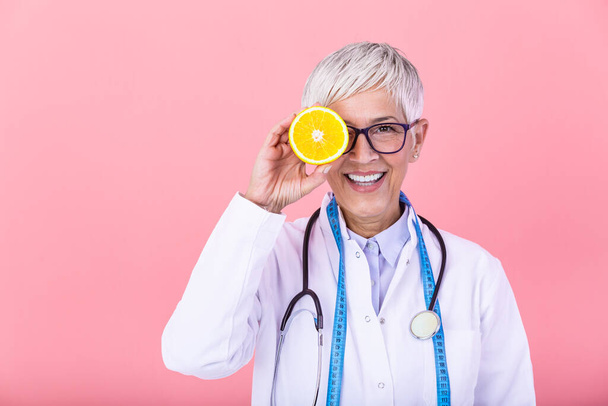 Dietician holding an orange. Smiling nutritionist holding a sliced orange, vitamins and healthy diet concept. Good medical healthcare nutrition concept. - Фото, изображение