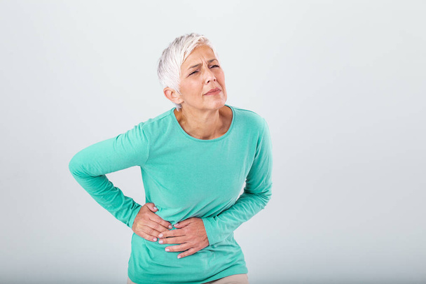 Elderly woman with gray hair touching her aching hip. Upset mature old woman touching back feel hurt osteoarthritis kidney spine ache sore muscles, sad senior lady suffer from lower lumbar pain - Foto, afbeelding