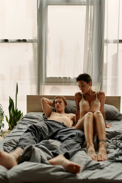 Shirtless man in pajama pants lying near sexy girlfriend on bed  - Photo, Image