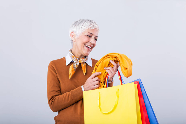 Happy mature good looking woman happy with her purchase, holding silk scarf looking at it and smiling. Shopping concept - Foto, Imagem