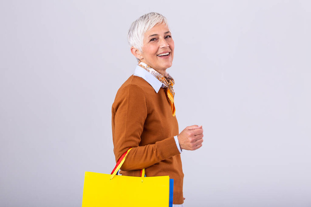 Portrait of a happy mature woman holding shopping bags and looking at camera isolated over white background - Φωτογραφία, εικόνα