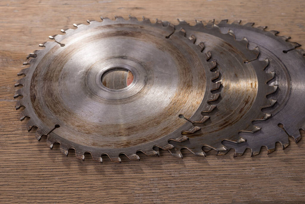 Used electric saw blades on a wooden background - 写真・画像