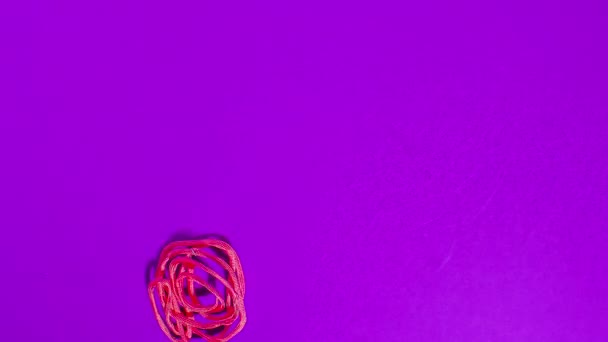 Stop motion animation of a cute pink wire flower appearing on purple background. - Imágenes, Vídeo