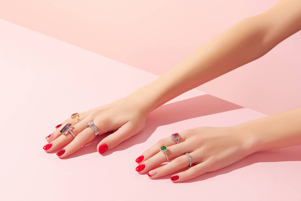 Womans hand with rinds on pink background. Jewelry accessory sale concept. - Φωτογραφία, εικόνα