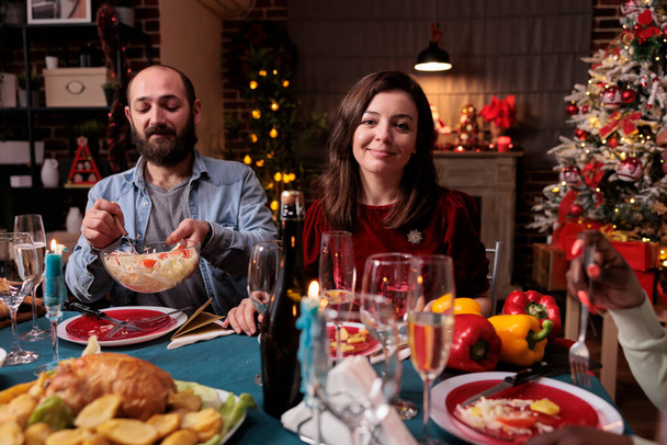 Пара святкує Різдво на сімейній домашній вечірці, щасливі друзі п'ють ігристе вино за святковим обіднім столом. Дружина і чоловік їдять додому приготовані різдвяні страви в прикрашеному красивому місці
 - Фото, зображення