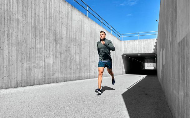 fitness, sport and healthy lifestyle concept - young man running out of tunnel - 写真・画像