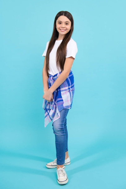 Full length of attractive cheerful teenager child girl in casual fashion clothes over blue isolated background. Happy teenager, positive and smiling emotions of teen girl - Фото, изображение