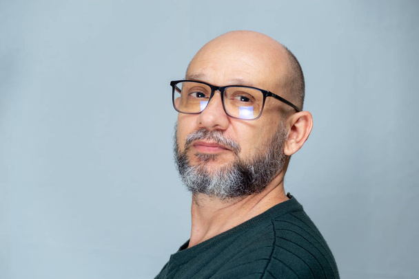 Portrait of mature man standing on light background. Bearded bald man in glasses. Formal style. - Foto, afbeelding
