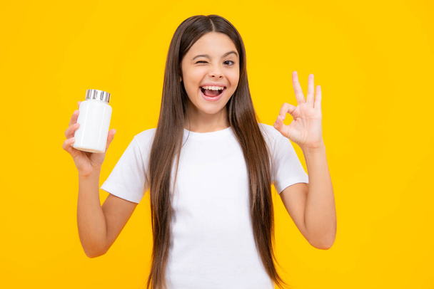 Staying healthy. Teenage girl holding vitamin pills on yellow isolated background. Excited teenager, glad amazed and overjoyed emotions - Fotó, kép