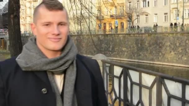 Young handsome man walk in city and smiles to camera - closeup - Materiał filmowy, wideo