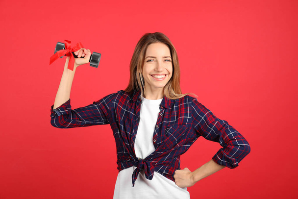 Woman with dumbbell as symbol of girl power on red background. 8 March concept - Foto, Imagen