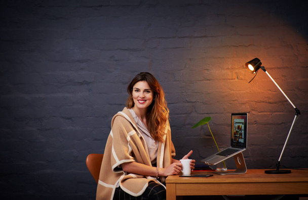 Портрет жінки, яка п'є каву, сидячи за столом зі своїм ноутбуком
 - Фото, зображення