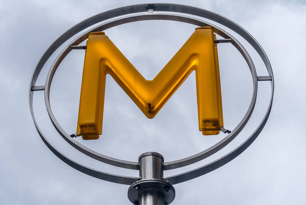 Lit žlutá Paříž metro znamení v hliníkovém kruhu proti zakalené obloze pozadí  - Fotografie, Obrázek
