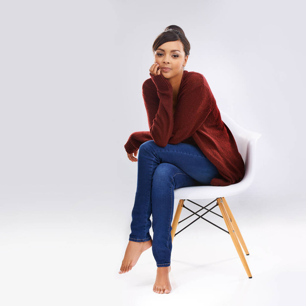 Simple style suits me fine. Studio portrait of an attractive young woman sitting on a chair - Fotó, kép