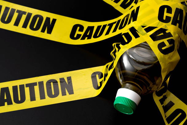Eine Flasche Pflanzenöl (Samenöle) im Warnband-Konzept für ungesunde ultraverarbeitete Lebensmittel, diätetische Warnungen für ein erhöhtes Entzündungsrisiko und entzündungsfördernde Omega-6-Fettsäuren - Foto, Bild