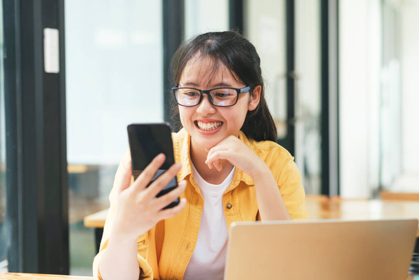 Jonge Aziatische vrouw student thuis studeren met behulp van laptop en online leren. Business freelancer videoconferentie via laptop thuis. - Foto, afbeelding