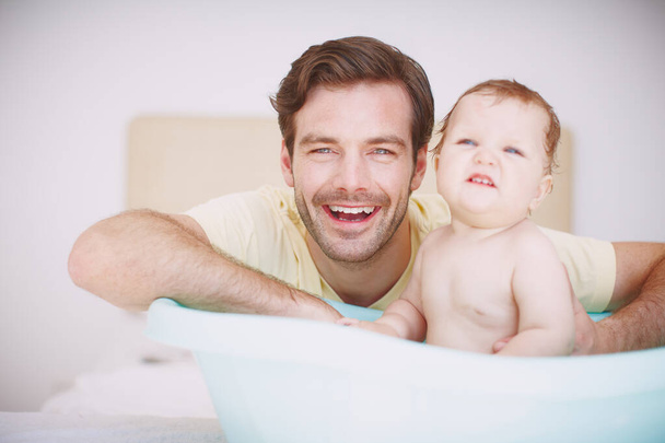 Temizlenmek günün gerekli bir parçası. Genç bir baba, banyo saatinde küçük kızıyla bağ kuruyor. - Fotoğraf, Görsel