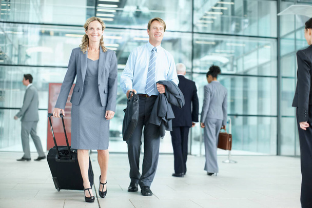 Business can take you around the world. Positive mature businesspeople arriving at an airport with their suitcases - Business Travel - Foto, imagen