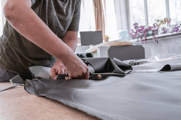 A cutter cuts fabric with scissors in a sewing workshop - Foto, Bild