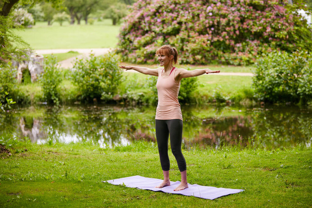 Getting back to nature with some yoga. a woman doing yoga in the park - Foto, Imagen