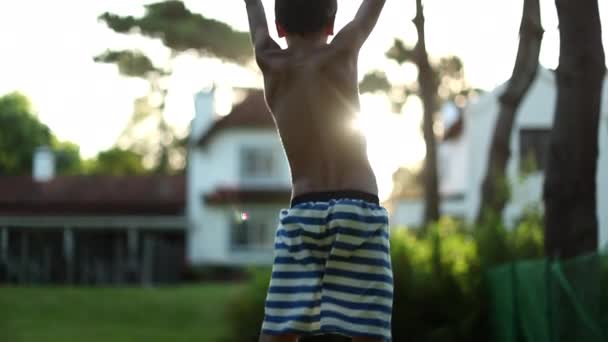 Çocuk sevinçle havaya zıplıyor. Gün batımının altın saatinde çocuk zaferle havada yumruk kaldırıyor. - Video, Çekim