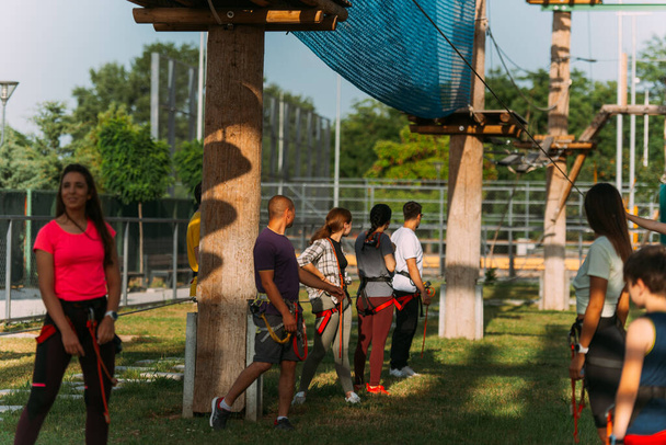 Grupo de escaladores observando a alguien bajando por la tirolina en el parque de aventuras - Foto, Imagen