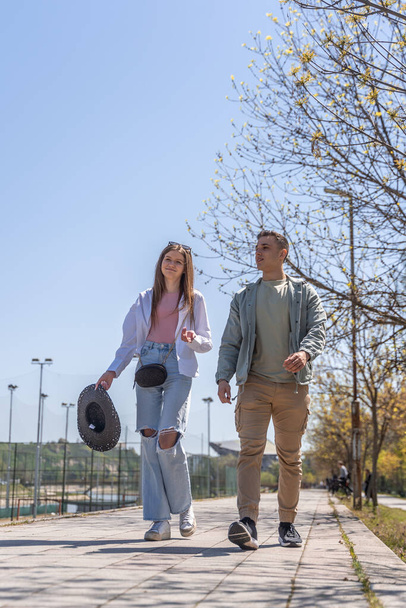 Молодой красивый мужчина и женщина, гуляющие в летнем парке и разговаривающие весело провести время вместе - Фото, изображение