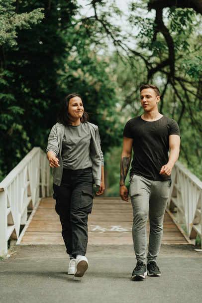 Schönes Paar spaziert in der Nähe der weißen Brücke im Park - Foto, Bild