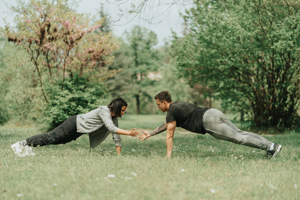 Beautiful couple working out on the grass in the park - Fotografie, Obrázek