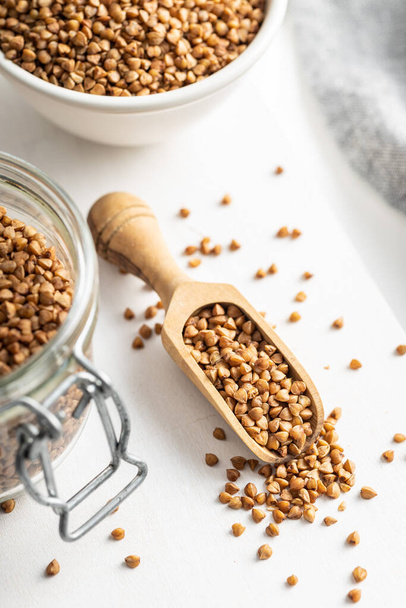Uncooked buckwheat grain in the wooden scoop. - Фото, изображение