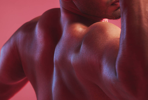 Sexy man, strong back and muscle bodybuilder in nude, fitness and skin against colorful studio background. Naked, healthy and powerful guy closeup with shoulder strength, muscular and flexing arms. - 写真・画像