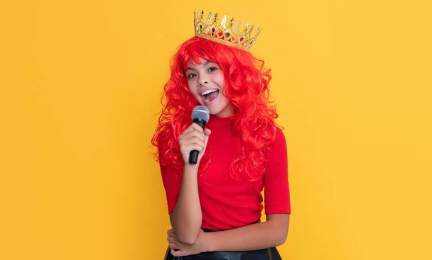 girl smile in crown with microphone on yellow background. - Φωτογραφία, εικόνα