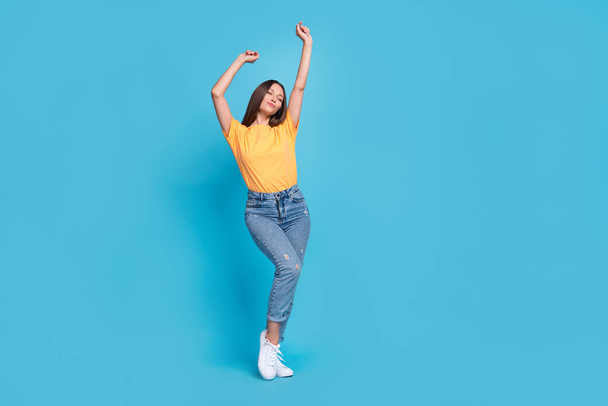 Full length photo of adorable dreamy girl dressed yellow t-shirt dancing closed eyes empty space isolated blue color background. - Fotografie, Obrázek