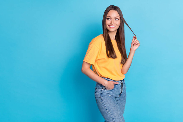 Photo of lovely sweet lady wear yellow clothes outfit arm touch strand hair interested look empty space isolated on blue color background. - Фото, зображення