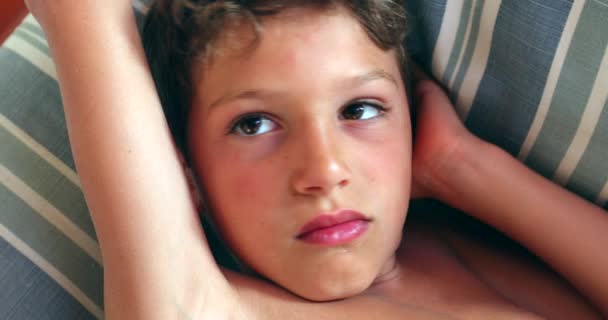 Znudzony chłopiec leżący na kanapie w domu - Materiał filmowy, wideo