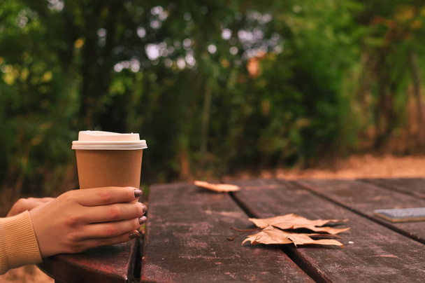 Paper glass of coffee in hand on the orange autumn leaves background . High quality photo - Foto, immagini