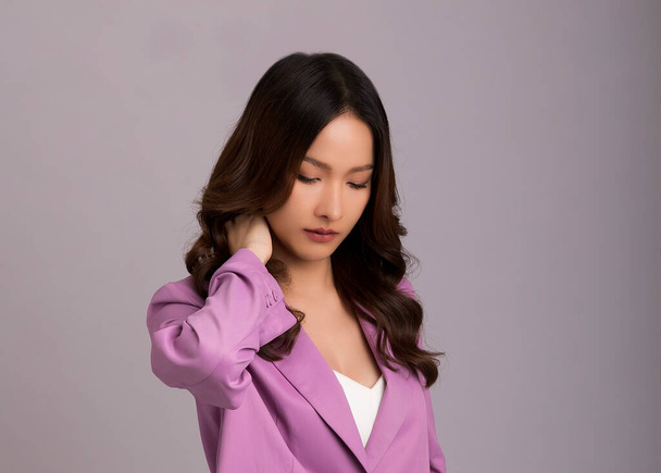 Asian woman wearing pink suit isolated on white background suffering from desperate stressed because of pain. Puts hands on neck. - Photo, image