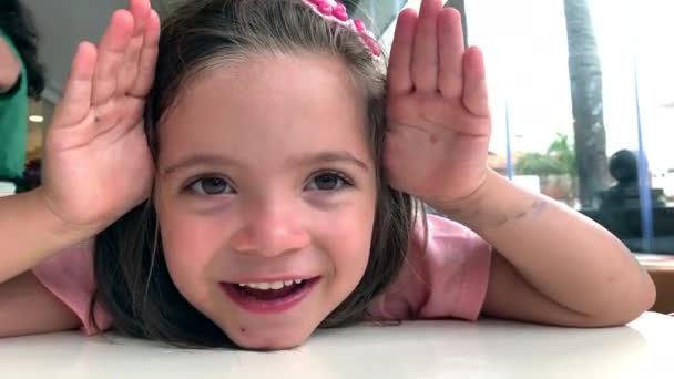 Cute little girl gra peekaboo pokrycie twarzy z rąk - Materiał filmowy, wideo