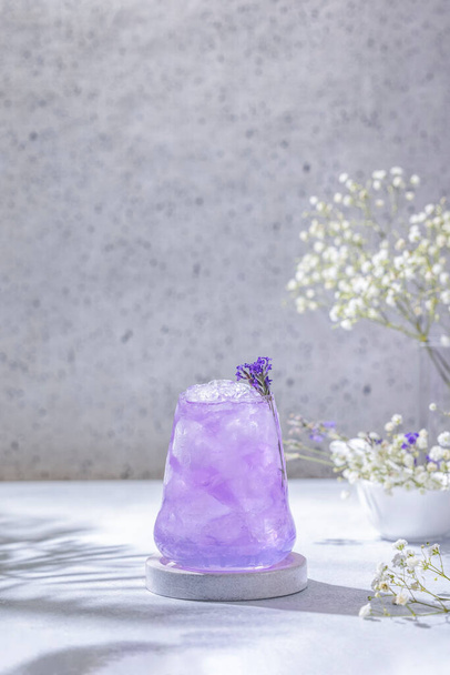 Lavender Gin and Tonic Punch Cocktail. Elegant glass filled with violet cocktail or mocktails surrounded by ingredients, lavender and white gypsophila flowers on light gray table surface. Ready for drinking. - Foto, afbeelding