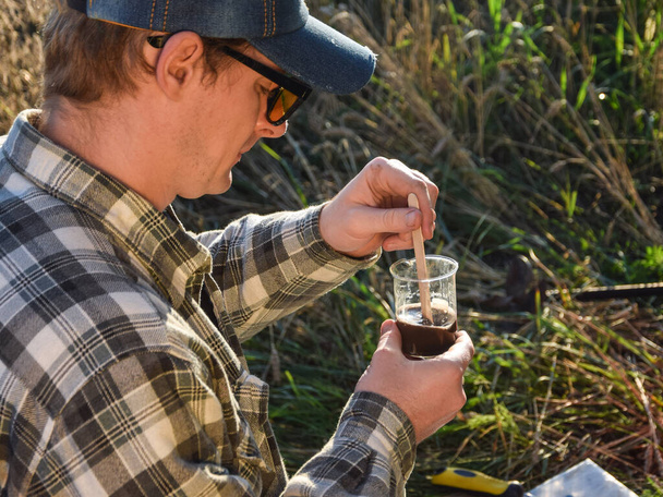 Male agronomy specialist testing soil sample outdoors, using laboratory equipment, performing soil certification at agricultural grain field sunrise. Environment research, soil certification - Foto, Imagem