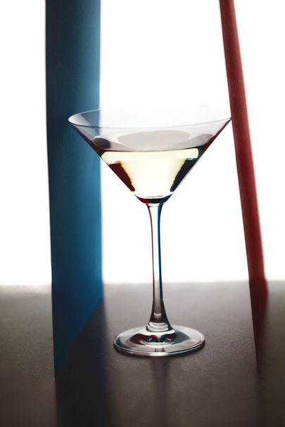 Martini glass and colored paper on a white background - Фото, изображение