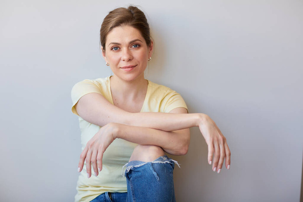 Resting woman sits with her back to the wall, isolated portrait happy girl in casual  clothes  - Foto, imagen