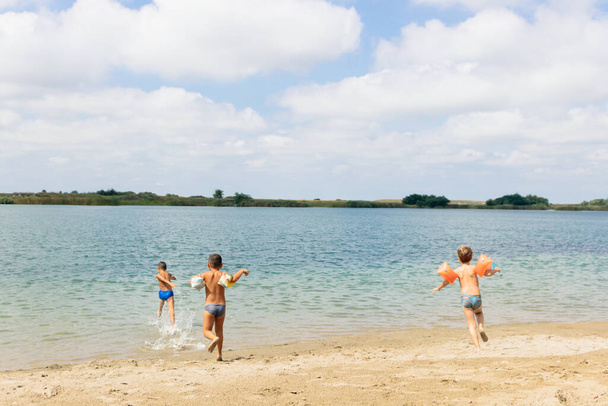 Группа беззаботных детей, бегающих в воде и веселящихся на пляже. Копирование пространства. - Фото, изображение