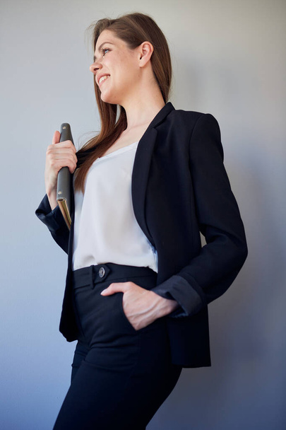 Smiling woman  teacher in black business suit and white shirt keeps hand in pants pocket looking away. isolated profile portrait. - Foto, imagen