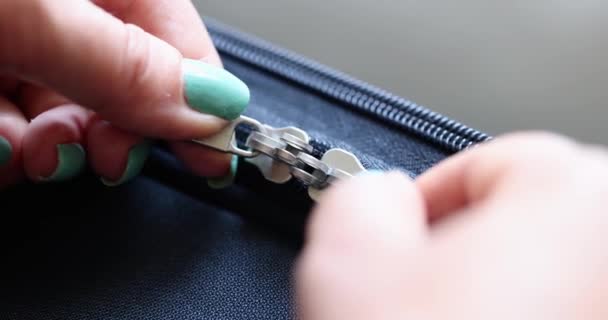 Womens hands open the lock on a zipper on a blue fabric, close-up. Repair of clothes, metal sewing accessories - 映像、動画